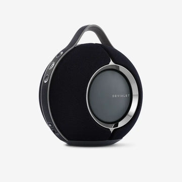 A black Devialet Mania Smart portable speaker with a round shape and a handle on top.